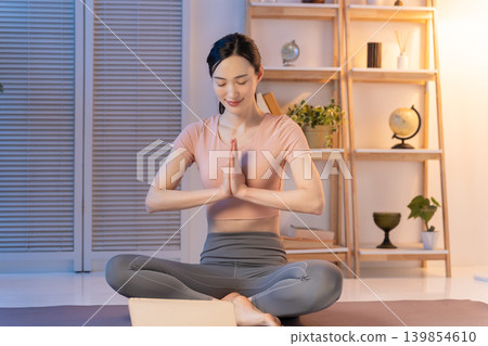 A woman doing yoga at night while watching a video. A woman doing yoga at night while watching a video. 139854610