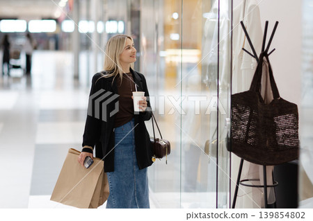 Young woman enjoying window shopping at a mall Young woman enjoying window shopping at a mall 139854802