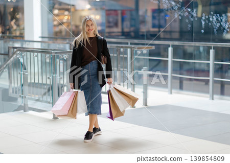 Woman enjoying shopping day carrying colorful bags Woman enjoying shopping day carrying colorful bags 139854809