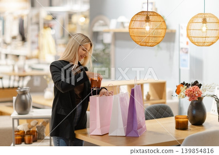 Woman smiling while arranging purchases in shopping bags 139854816