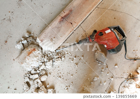 Electric demolition hammer on floor with broken concrete debris Electric demolition hammer on floor with broken concrete debris 139855669