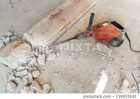Electric demolition hammer on floor with broken concrete debris Electric demolition hammer on floor with broken concrete debris 139855681
