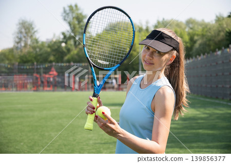 Young woman tennis player holding racket and ball on outdoor sports court Young woman tennis player holding racket and ball on outdoor sports court 139856377