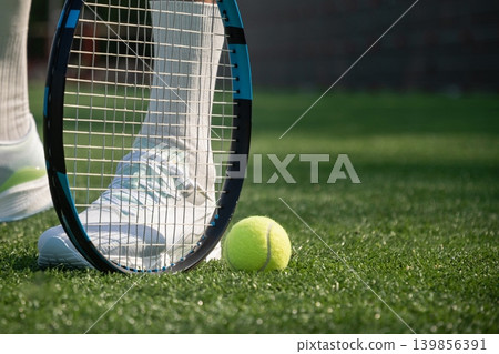 Tennis ball and racket on green outdoor court Tennis ball and racket on green outdoor court 139856391
