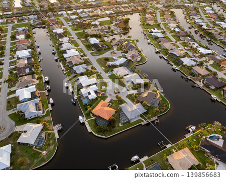 Sunset aerial view of luxurious waterfront mansions in Florida. Premium housing development with tropical palms and elegant residential homes. Sunset aerial view of luxurious waterfront mansions in Florida. Premium housing development with tropical palms and elegant residential homes. 139856683