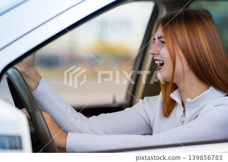 Closeup portrait of pissed off displeased angry aggressive woman driving a car shouting at someone with hand fist up. Negative human expression consept. Closeup portrait of pissed off displeased angry aggressive woman driving a car shouting at someone with hand fist up. Negative human expression consept. 139856783