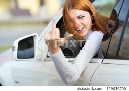 Pissed off displeased angry aggressive woman driving a car shouting at someone with middle finger gesture. Pissed off displeased angry aggressive woman driving a car shouting at someone with middle finger gesture. 139856790