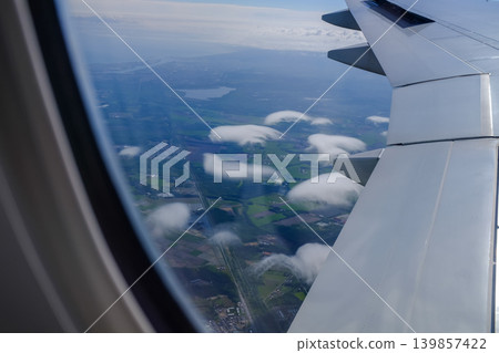 Looking from the airplane window with stunning skyscapes and landscape with airplane wing. Travel and transportation concept. Looking from the airplane window with stunning skyscapes and landscape with airplane wing. Travel and transportation concept. 139857422