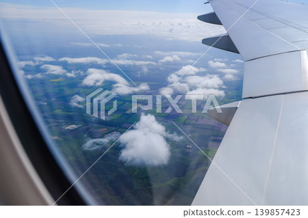 Looking from the airplane window with stunning skyscapes and landscape with airplane wing. Travel and transportation concept. Looking from the airplane window with stunning skyscapes and landscape with airplane wing. Travel and transportation concept. 139857423