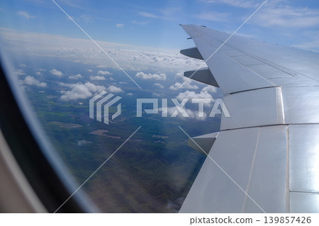 Looking from the airplane window with stunning skyscapes and landscape with airplane wing. Travel and transportation concept. Looking from the airplane window with stunning skyscapes and landscape with airplane wing. Travel and transportation concept. 139857426