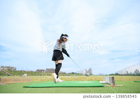 Japanese woman swinging a golf club Japanese woman swinging a golf club 139858543