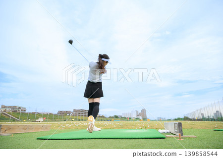 Japanese woman swinging a golf club Japanese woman swinging a golf club 139858544