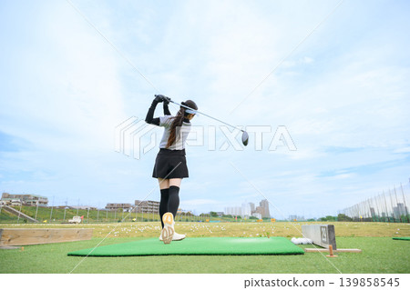 Japanese woman swinging a golf club Japanese woman swinging a golf club 139858545