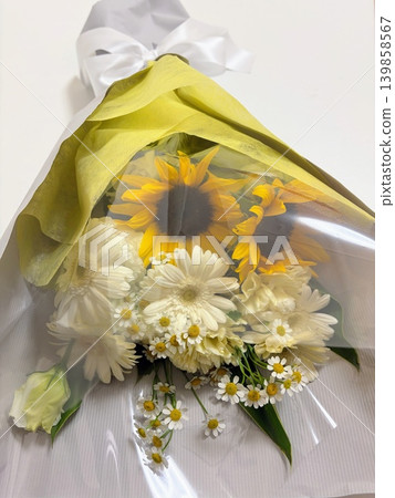 A sunflower bouquet with a white ribbon and yellow wrapping. A sunflower bouquet with a white ribbon and yellow wrapping. 139858567