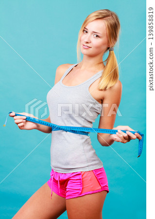 Fitness girl measuring her waistline Fitness girl measuring her waistline 139858819