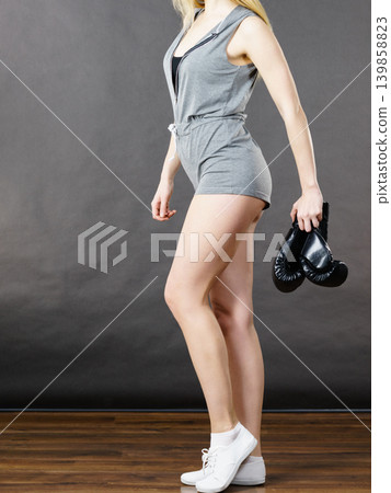 Woman holding boxing gloves after fight Woman holding boxing gloves after fight 139858823