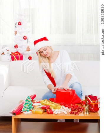 Woman in Santa hat packing christmas gifts Woman in Santa hat packing christmas gifts 139858930