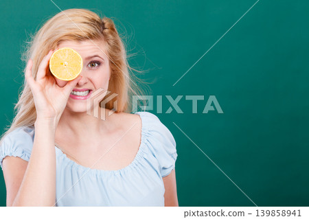 Girl covering her eye with lemon citrus fruit Girl covering her eye with lemon citrus fruit 139858941