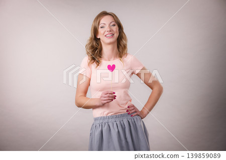 Happy woman holding heart on stick Happy woman holding heart on stick 139859089
