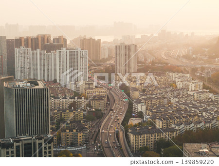 A major highway filled with vehicles stretches through a large urban area featuring modern high-rise buildings and older residential blocks A major highway filled with vehicles stretches through a large urban area featuring modern high-rise buildings and older residential blocks 139859220