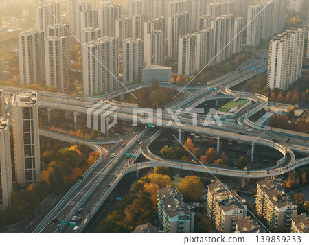 Cars move on a multi-level highway interchange cutting through a city filled with numerous tall residential and commercial structures Cars move on a multi-level highway interchange cutting through a city filled with numerous tall residential and commercial structures 139859233