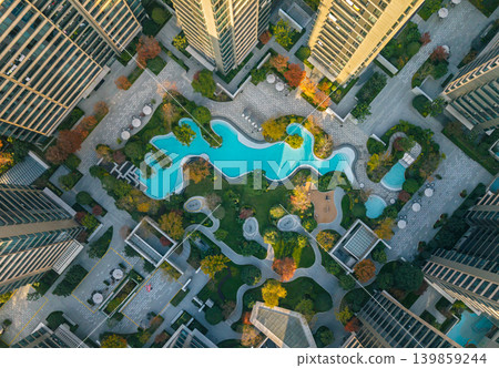 Overhead view of a large urban residential complex. Numerous modern high-rise buildings surround a park with bright blue swimming pools Overhead view of a large urban residential complex. Numerous modern high-rise buildings surround a park with bright blue swimming pools 139859244