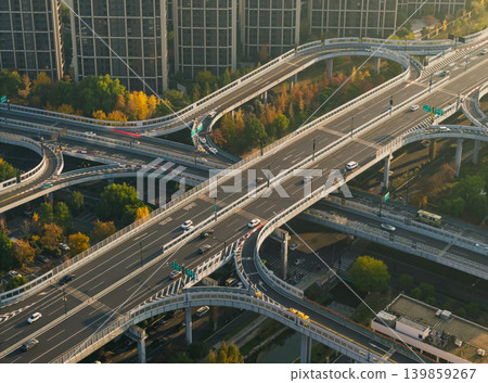 Cars move on a multi-level highway interchange cutting through a city filled with numerous tall residential and commercial structures Cars move on a multi-level highway interchange cutting through a city filled with numerous tall residential and commercial structures 139859267