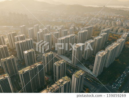 High-rise residential buildings dominate a dense urban landscape, arranged around wide roads and a central intersection High-rise residential buildings dominate a dense urban landscape, arranged around wide roads and a central intersection 139859269