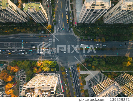 Busy city intersection from above with cars, a red bus, and other vehicles navigating multi-lane roads. Pedestrians cross the street Busy city intersection from above with cars, a red bus, and other vehicles navigating multi-lane roads. Pedestrians cross the street 139859271