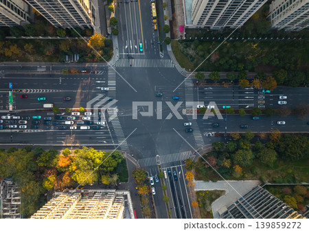 Busy city intersection from above with cars, a red bus, and other vehicles navigating multi-lane roads. Pedestrians cross the street Busy city intersection from above with cars, a red bus, and other vehicles navigating multi-lane roads. Pedestrians cross the street 139859272