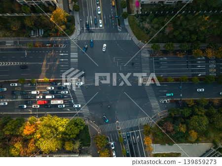 Busy city intersection from above with cars, a red bus, and other vehicles navigating multi-lane roads. Pedestrians cross the street 139859273