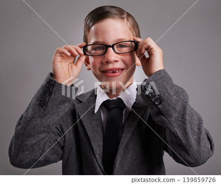 Portrait, costume and boy with glasses, business and Halloween dress up on a grey studio background, Face, person and model with vision and eyewear with child development and smile with retro clothes Portrait, costume and boy with glasses, business and Halloween dress up on a grey studio background, Face, person and model with vision and eyewear with child development and smile with retro clothes 139859726