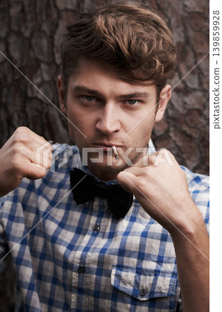 Fight, smoking and portrait of man in outdoors for challenge, strong and fighting. Cigarette, hipster and anger with face of male person and hands up in nature for combat, cool and trendy style Fight, smoking and portrait of man in outdoors for challenge, strong and fighting. Cigarette, hipster and anger with face of male person and hands up in nature for combat, cool and trendy style 139859928