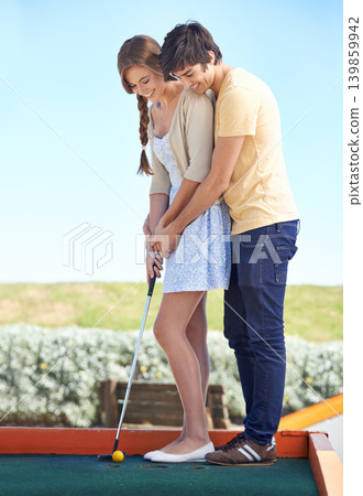 Young couple, love and outdoor for mini golf in nature, bonding together and happy on weekend with hobby. Man, woman and putt on romantic trip and care, sunshine and teaching girlfriend to play game Young couple, love and outdoor for mini golf in nature, bonding together and happy on weekend with hobby. Man, woman and putt on romantic trip and care, sunshine and teaching girlfriend to play game 139859942