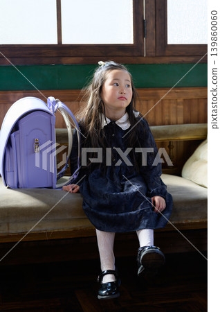 A Japanese girl with a schoolbag sitting on a sofa A Japanese girl with a schoolbag sitting on a sofa 139860060