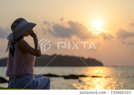 一位日本女性背對著鏡頭,在沖繩欣賞日落。 一位日本女性背對著鏡頭,在沖繩欣賞日落。 139860103