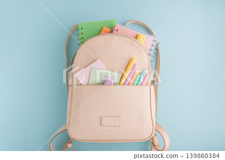 Pastel school supplies into backpack on blue background Pastel school supplies into backpack on blue background 139860384