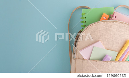 Pastel school supplies into backpack on blue background Pastel school supplies into backpack on blue background 139860385