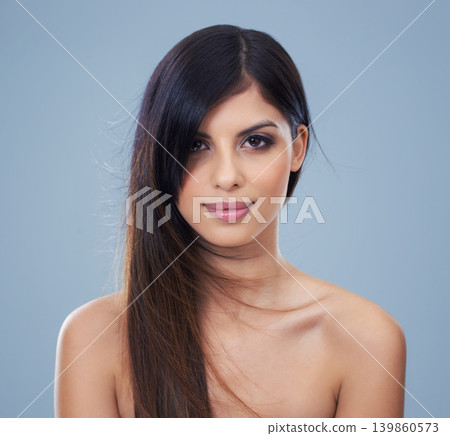 Studio, model and portrait with long hair for beauty, mock up and keratin treatment with salon result. Arab woman, face and confident with conditioner for hairdresser and skincare by blue background Studio, model and portrait with long hair for beauty, mock up and keratin treatment with salon result. Arab woman, face and confident with conditioner for hairdresser and skincare by blue background 139860573