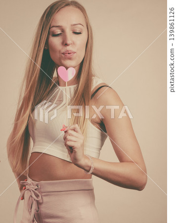 Happy woman holding heart on stick Happy woman holding heart on stick 139861126