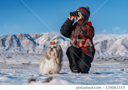 Child with binoculars and shih tzu dog posing on mountains background at winter Child with binoculars and shih tzu dog posing on mountains background at winter 139861555