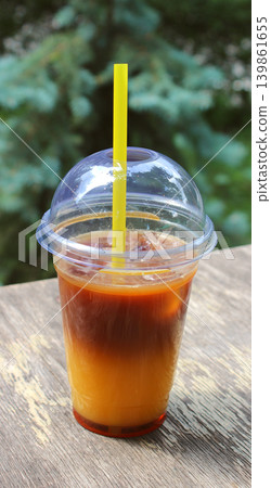 Ice Melting In Cup Of Iced Bumblebee Cocktail With Bright Yellow Straw On A Table At Open Air Bar  139861655