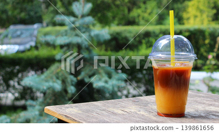 A small table with a cup of iced orange coffee takeaway cocktail in an outdoor cafe A small table with a cup of iced orange coffee takeaway cocktail in an outdoor cafe 139861656
