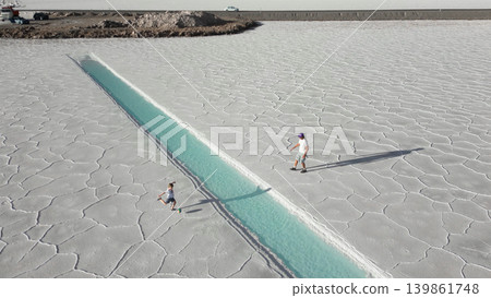 Aerial view of father and child playing football onwhite salt flats Salinas Jujuy Argentina Aerial view of father and child playing football onwhite salt flats Salinas Jujuy Argentina 139861748
