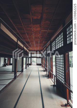 A traditional Japanese house with a long, deep corridor covered in tatami mats, offering a view of a Japanese garden. A traditional Japanese house with a long, deep corridor covered in tatami mats, offering a view of a Japanese garden. 139862225