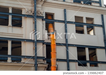 Waste chute used in construction demolition garbage. Suspended sections of a construction garbage chute on the facade of a historic building undergoing renovation. Safe waste disposal. 139862407