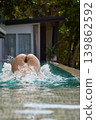 a girl with a beautiful tanned body having fun in the swimming pool of a luxury villa, the girl's butt is visible from under the water, azure water, splashes of water glow in the sun 139862592