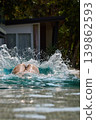 a girl with a beautiful tanned body having fun in the swimming pool of a luxury villa, the girl's butt is visible from under the water, azure water, splashes of water glow in the sun 139862593