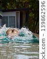 a girl with a beautiful tanned body having fun in the swimming pool of a luxury villa, the girl's butt is visible from under the water, azure water, splashes of water glow in the sun 139862596
