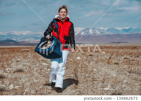 Young woman traveling with shih tzu dog in bag on winter mountains background 139862673